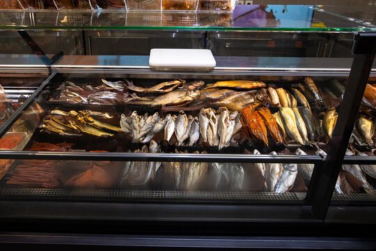 Assorted Dried and Smoked Fish Arranged on Shelves in Supermarket Refrigerator Showcase