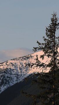Time-lapse of majestic snow-covered mountain peaks at sunrise, golden light rapidly shifts over rugged slopes, shadows dance across the landscape, capturing nature s serene yet dynamic transformation