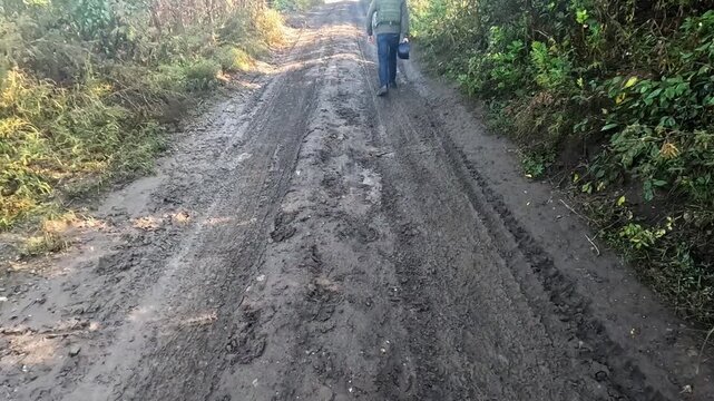 Volunteers in protective uniform walking on dirty country road at frontline city in Ukraine. Rescue workers going to help animals and people from areas shelled by russian army. Slow mo