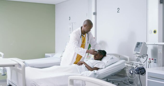 African American doctor entering ward leaning over teenage patient, placing O2 mask for breathing