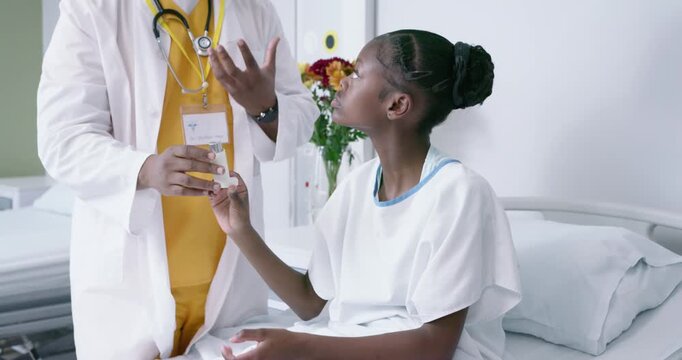 African American female patient learning inhaler technique after clinician hands device at bedside