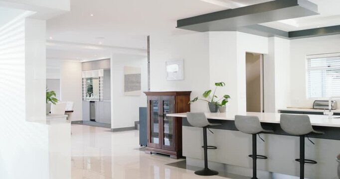 Camera starting rightward pan, island with gray bar stools revealing dining area, exposing layout