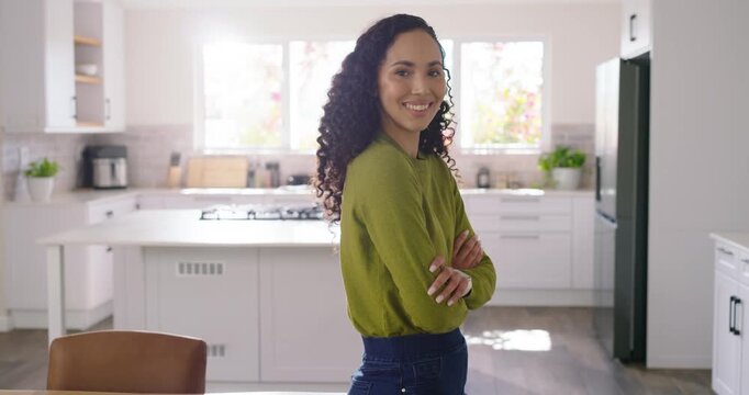 African American woman leaning on table in kitchen with camera approaching, relaxing, welcoming
