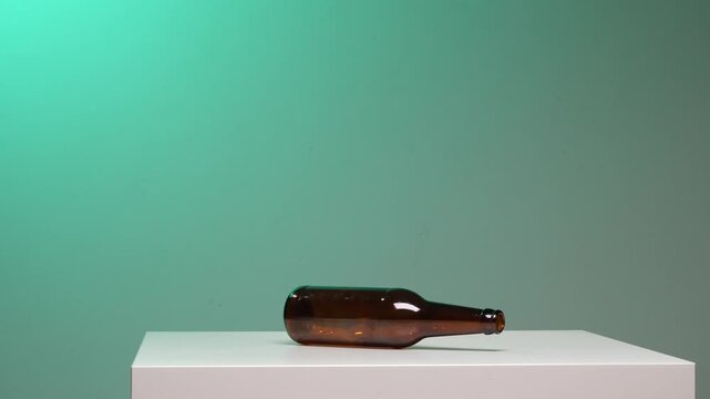 Hand spinning a brown glass bottle on a white surface to start a playful truth or dare game among friends, capturing motion, chance, and social decision making