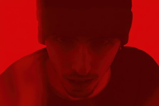person in a dark red environment looking down with a serious expression