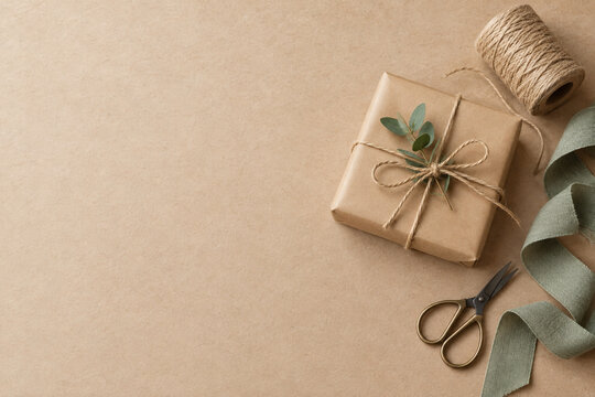 Kraft gift wrapping with twine and scissors on paper background