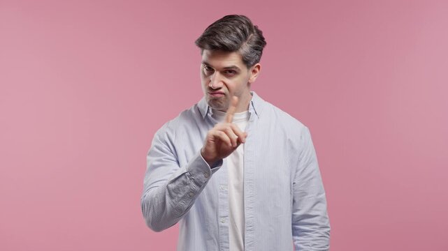Serious Uninterested Handsome Man Disapproving With Stop Finger Sign. Dont Play with me, enough. Portrait of guy on pink background