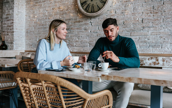 two hispanics friends enjoying food and drinks in restaurant, or happy diverse couple of people having meal and having fun