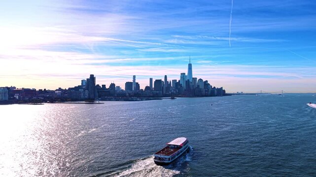 Catching up with the boat moving by the Hudson River at daytime. Prominent New York City skyscrapers in the skyline in the backdrop.