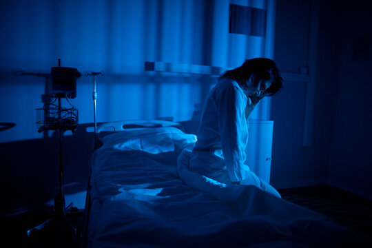 Patient in quiet distress. Person reclines under soft ambient light. Patient rests quietly in dimly illuminated space surrounded by gentle machine sounds and solitude