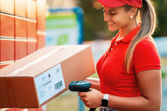 Female delivery courier scanning a parcel barcode with a handheld reader outdoors