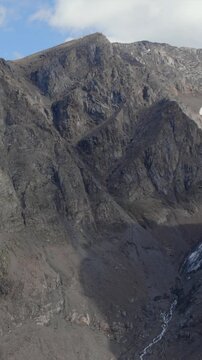 Drone footage sweeps across the ice-filled cirque and fractured summits of Aktru Valley, Altai Republic, Russia, revealing a secluded alpine basin beneath moving clouds in a vast highland setting