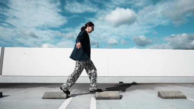 Woman Balancing on Parking Block Under Blue Sky