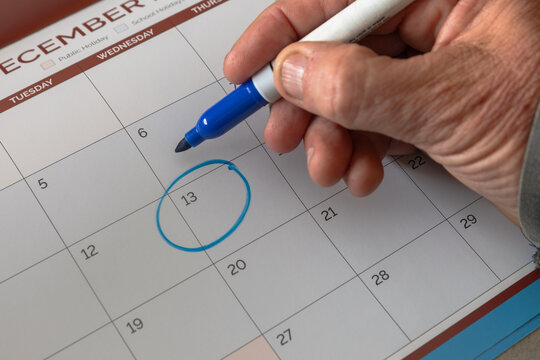 A tradesmen marks a date on a calendar with a blue marker pen.