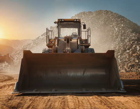 Heavy industrial wheel loader machine working in quarry at sunset