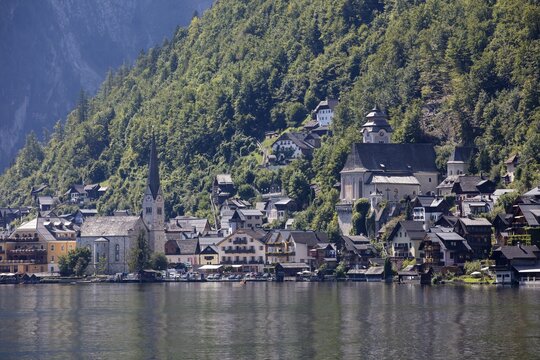 A, Hallstatt, A picturesque mountain village with lakeside churches in front of a steep forest slope, Austria