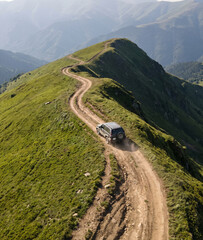 4x4 Off Road Vehicle Driving on Winding Dirt Road Along Dramatic Alpine Mountain Ridge © Ash