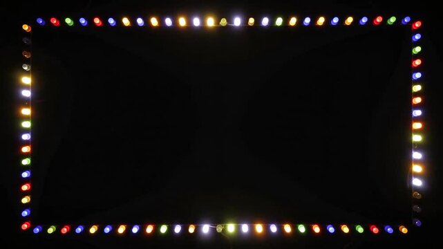 Colorful blinking Christmas lights arranged in a rectangular border frame flashing and glowing against a solid black background for festive holiday video projects 4k UHD Video