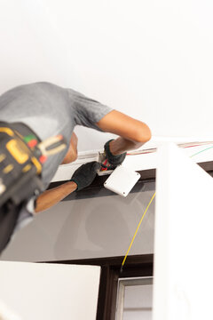Electrician wearing protective gloves wiring an indoor wall junction box.
