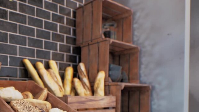 Wooden crates display fresh bread and golden baguettes on a dark brick wall background in a bakery