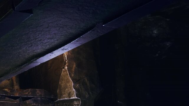 Dark cavern interior with natural rock formations and a smooth dark ceiling during night exploration