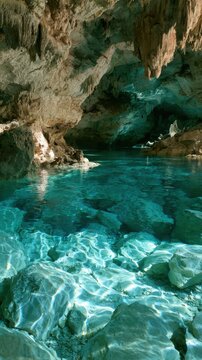 Flooded cenote cave with crystal clear turquoise water and rocks