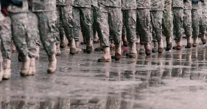 Romanian army soldiers march during a military ceremony on a rainy day.