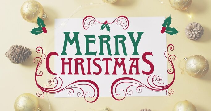 Showing greeting card with text on yellow tabletop, holly stickers, gold baubles, pinecones, lights