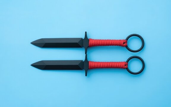 Black Ninja Throwing Stars with Red Cord Handles on Blue Background