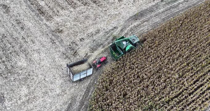 Aerial diagonal footage of a combine harvester and tractor moving along a harvested path through autumn corn fields in Inner Mongolia, China, showing modern mechanical farming and harvest patterns.
