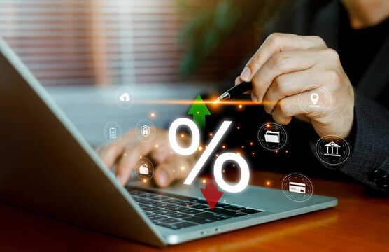 Business person using a laptop with a glowing percentage sign and financial interest rate icons. Concept of banking loan rate, economy inflation, investment return, and monetary policy.
