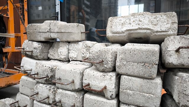 Stacked concrete blocks at a construction site. Heavy interlocking cement blocks piled up outdoors during building work.