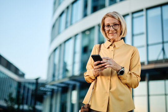 Businesswoman talking on phone with suitcase outdoors