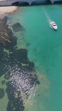 Aerial view of motorboat anchored near green coast of Cunda Island, Ayvalik. Vertical drone footage for summer travel and vacation. High quality 4k footage