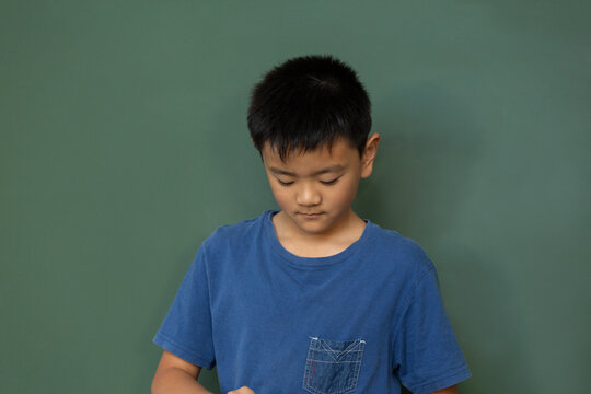 Schoolboy standing against green chalkboard in a classroom