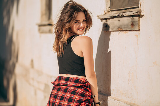 Western girl in 90s-style grunge clothing stands on the street during the day.