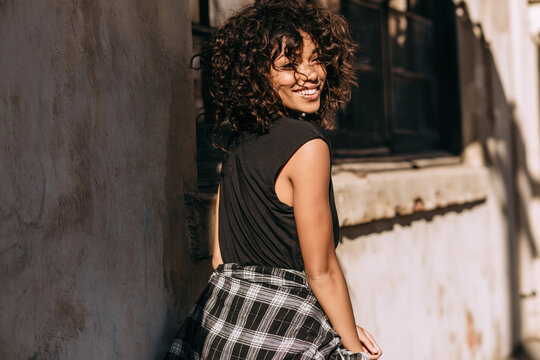 An African American girl in 90s-style grunge clothing stands on the street during the day.