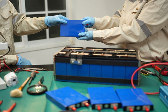 The skilled technician works on the lithium phosphate battery circuit board with his partner.