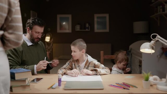 Family prepares to help son with homework at home. Parents help child start schoolwork at home. Parenting education teamwork family concept