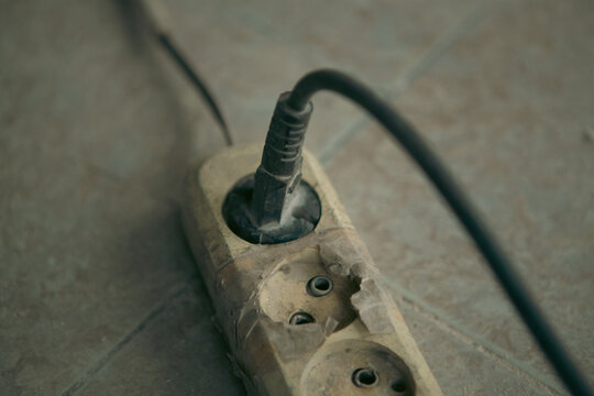 Electric plug and socket on a tile floor. Old electrical outlet.