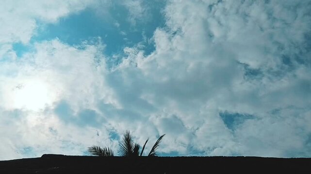 Bright sunlight shining through white clouds in a blue sky above a dark horizon sun weather cloudscape daytime light