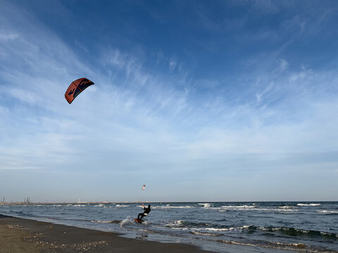 Kitesurfer  riding waves in the sea under a dramatic sky. 