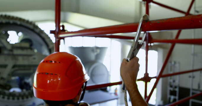 Construction worker assembles scaffolding indoors, with copy space