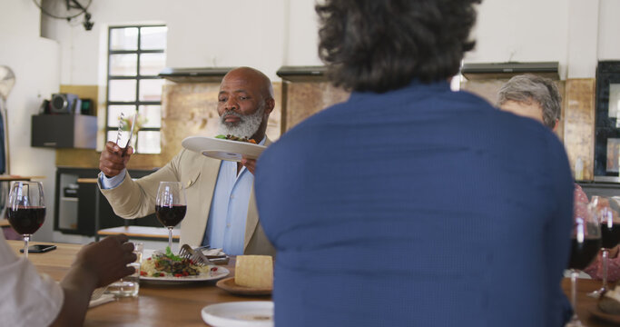 Diverse senior group enjoying meal at table in kitchen