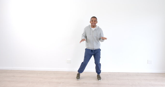African American man dancing joyfully in casual outfit on wooden floor