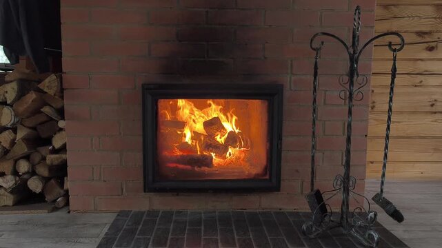 Cozy fireplace with fire tools and woodpile preparedness for energy disruptions. A stove that keeps home warm in winter. Savings on electricity, fuel and other resources. crisis in heating sector.