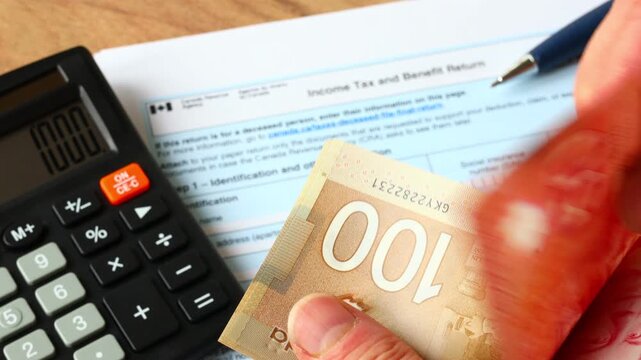 Canada Tax Return: Person holding and counting CAD banknotes while calculating and completing the T1 Income Tax and Benefit Return document.