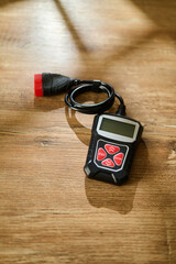 Handheld digital meter with a coiled cable resting on a wooden floor © mira_y