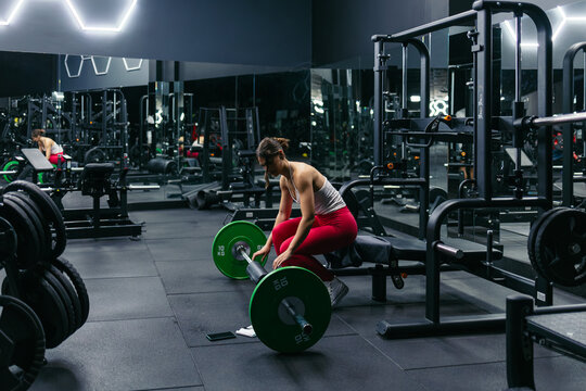 Woman preparing a barbell for hip thrust training in a gym