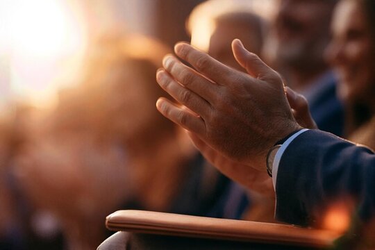 Man applauds during an outdoor gathering at sunset